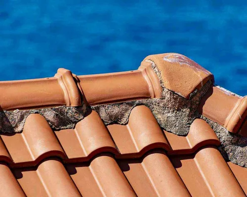 Impact-Roof-Maintenance-01 Close up picture of a concrete or terracotta tiled roof with patchy concrete pointing showing a need to redo the pointing on the roof.